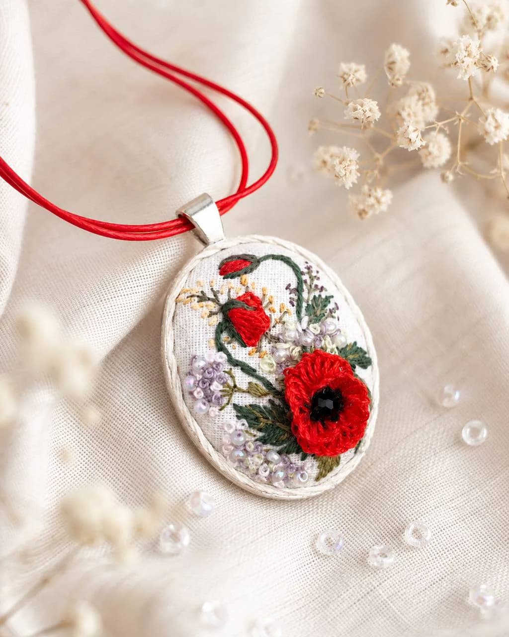 Handgefertigter bestickter Anhänger mit rotem Mohn, grünen Blättern und Perlenstickerei auf hellem Stoffgrund — künstlerisches Rendering des Anhängers 2, NataSko Handmade